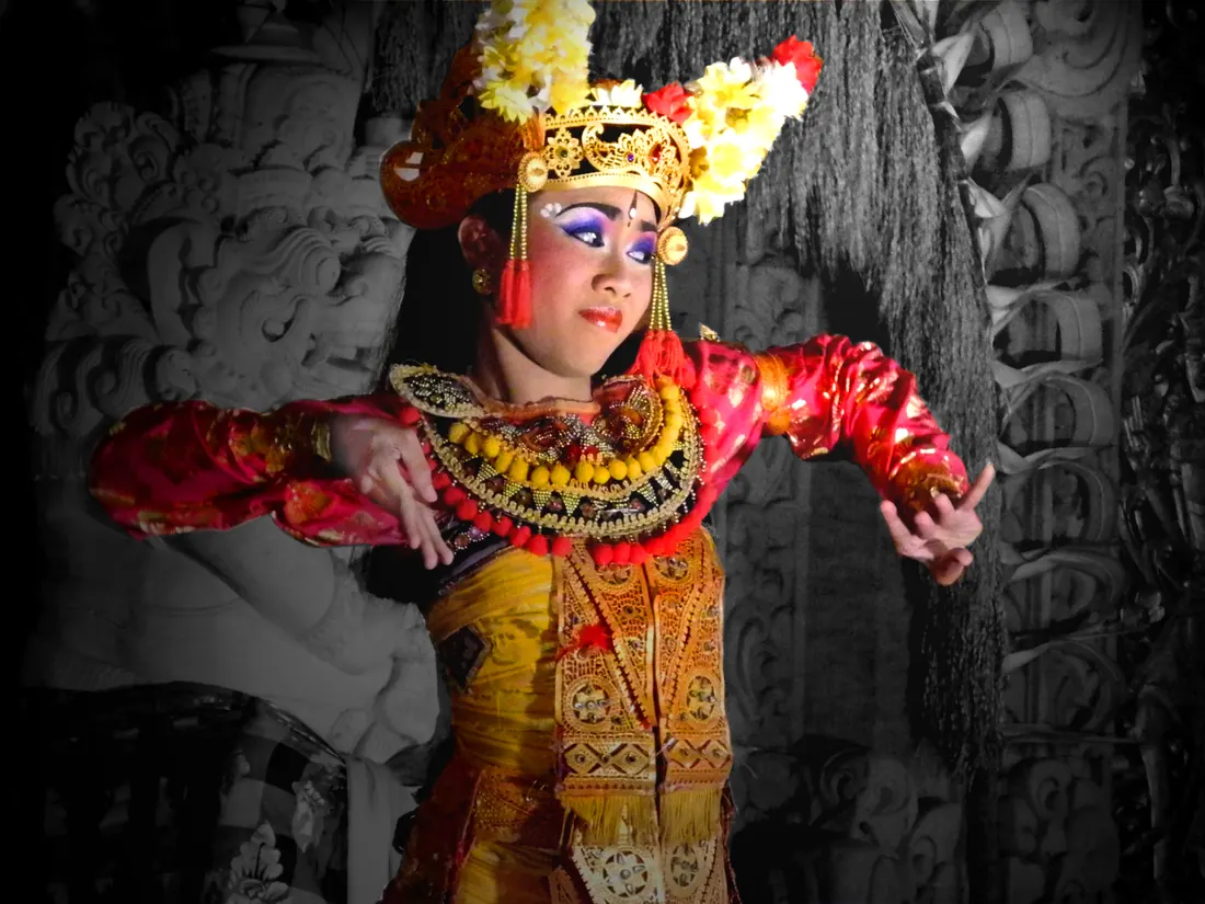 A Balinese Legong dancer in an ornate gold headdress and costume, mid-pose